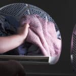 A man taking a fleece blanket out of the dryer.