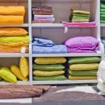 Bright pillows, plaids, blankets and other bedroom wear on shelves